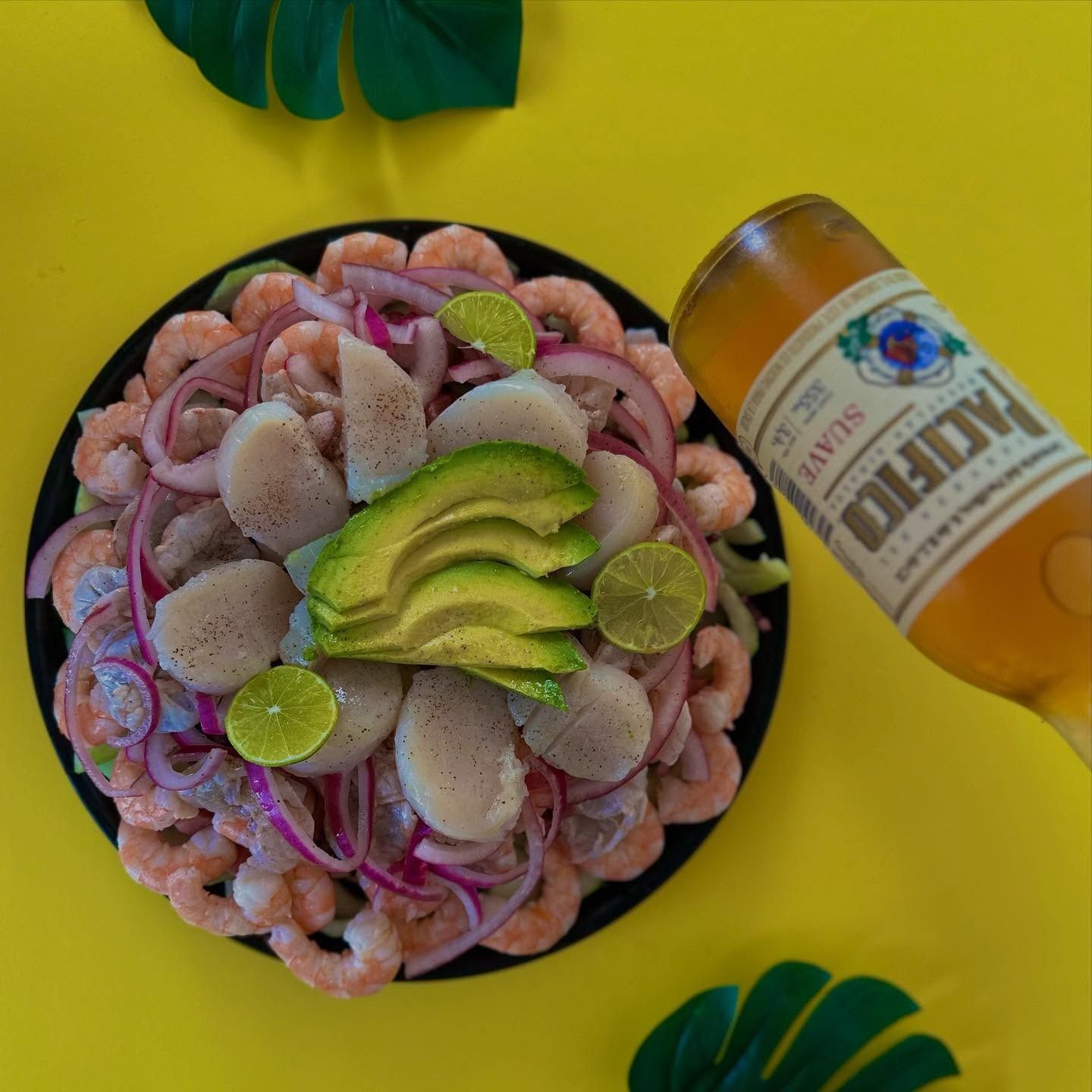 Ceviche de camarón y callo con cebolla morada, limón y aguacate junto a una cerveza Pacífico