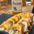 Rollo empanizado con salsa naranja y una cerveza Pacífico al fondo