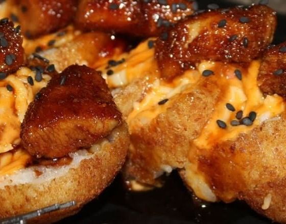 Bocados glaseados con ajonjolí negro sobre salsa naranja