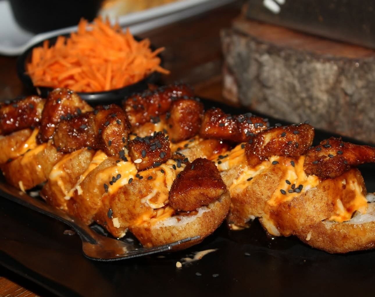 Rollo empanizado con bocados glaseados, salsa naranja y ajonjolí negro